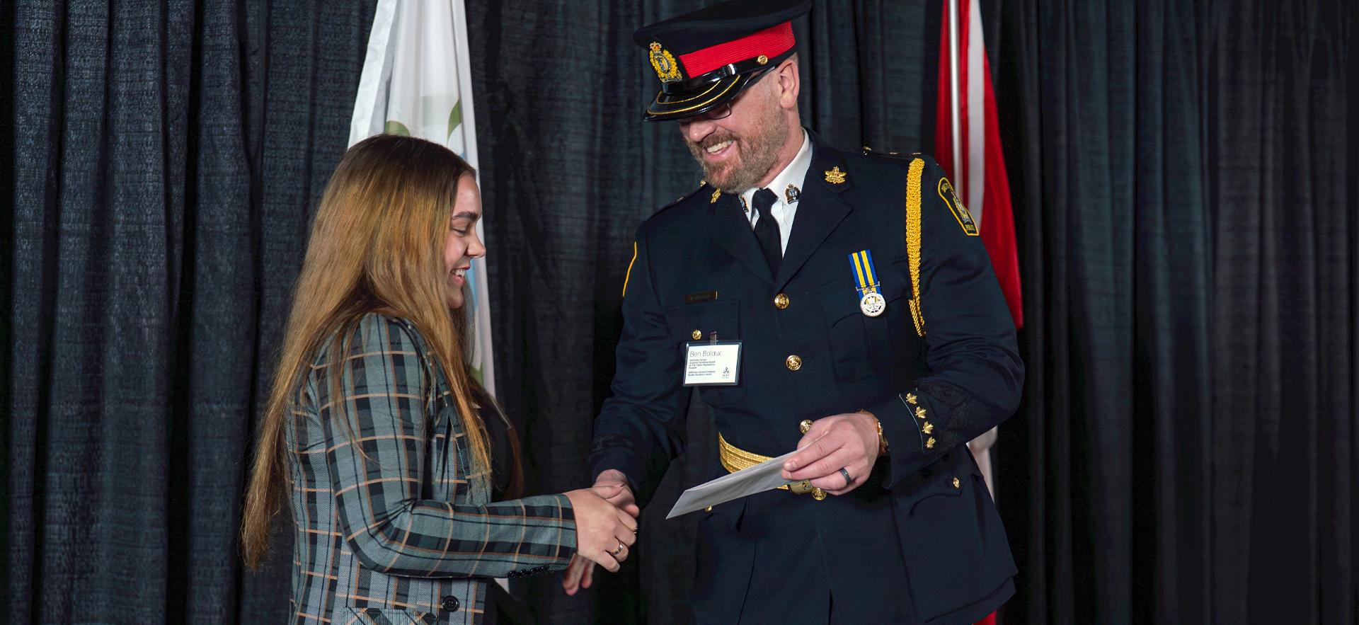 Student receiving award on stage from police officer at awards event night