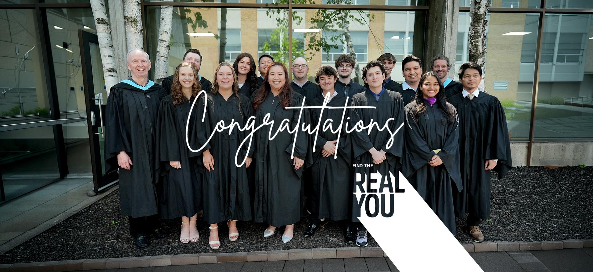 Group of graduating students with faculty in grad gowns posed together outdoors