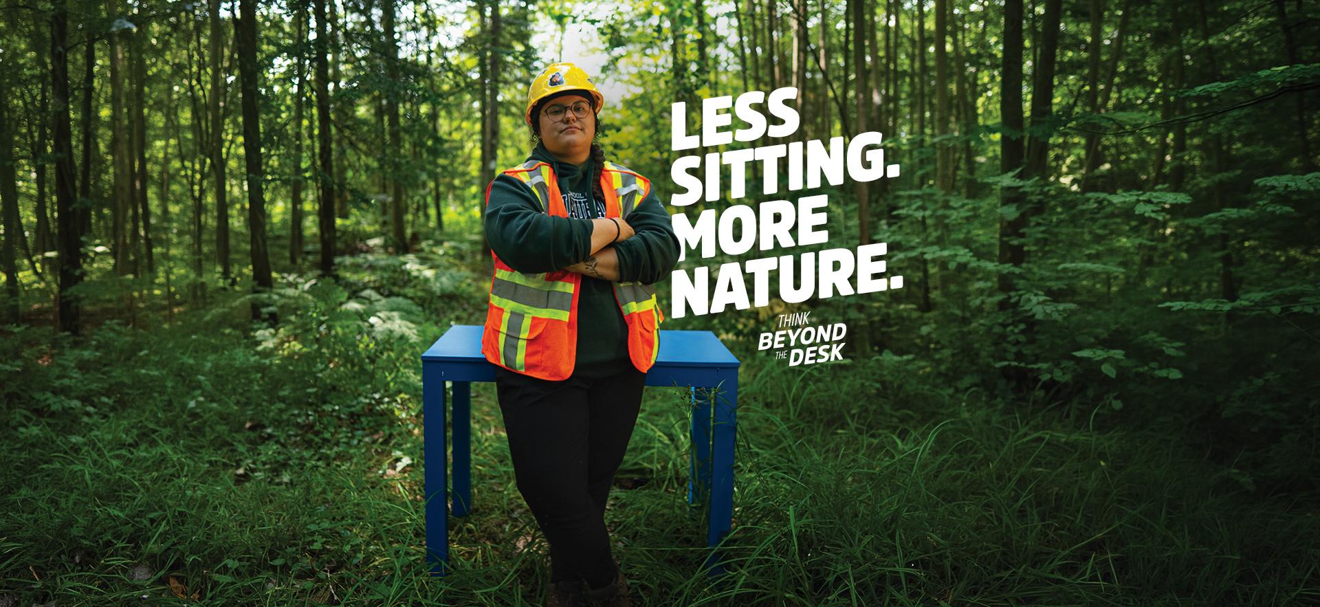 Natural Environment student leaning against blue desk in outdoor lab