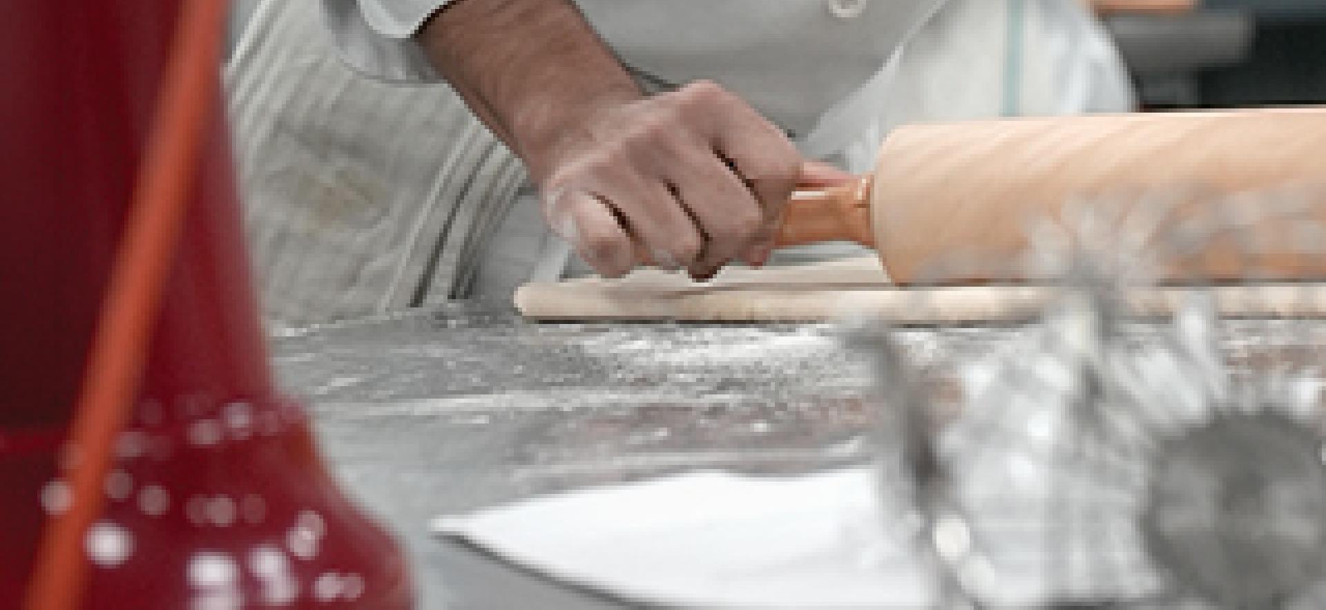 Culinary student rolling out dough in baking lab