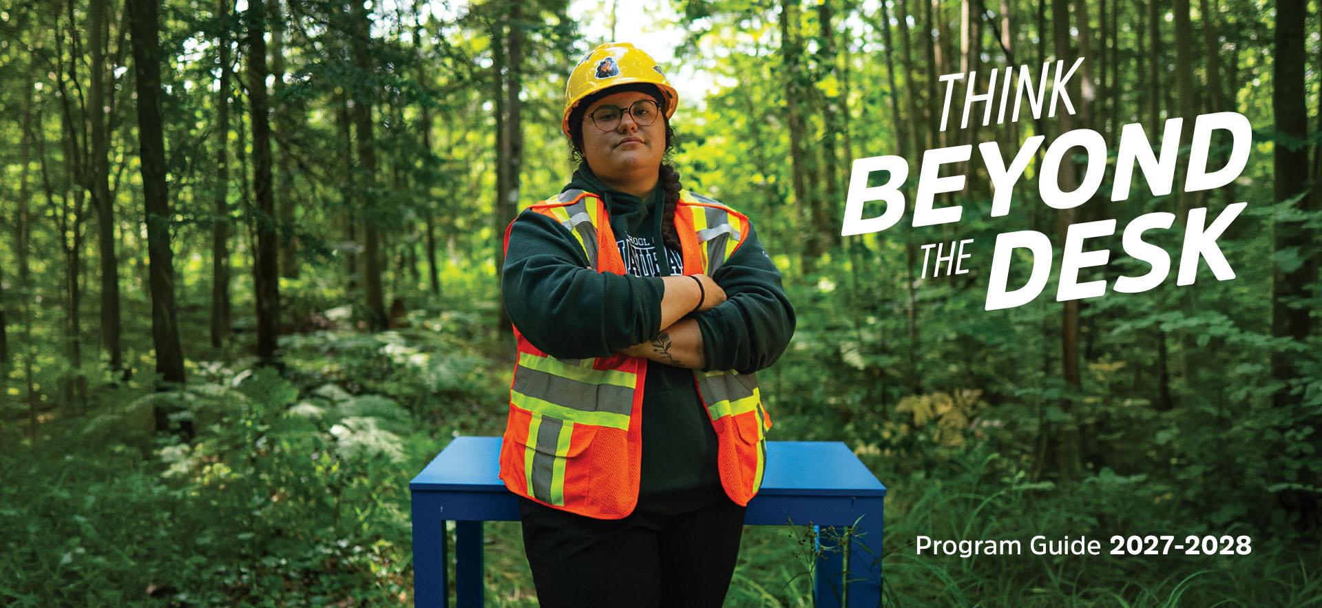 School of Natural Environment student leaning against blue desk outdoors in uniform