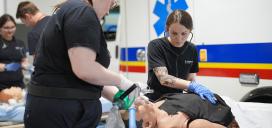 Paramedic students practicing skills in lab with manikin on stretcher