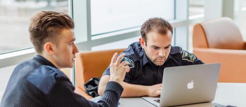 Two male Police Foundations students discuss a class project.