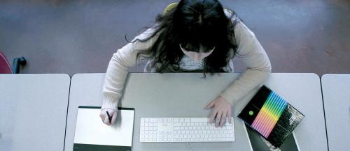 A female Graphic Design - Digital Media student works at her computer in class.