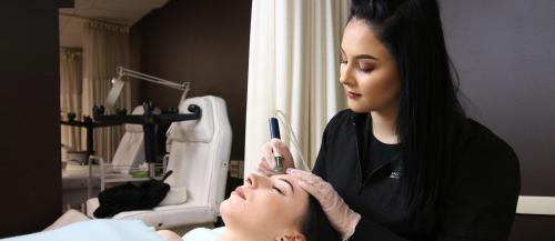 One female Esthetician student applies a skin treatment to another student in the Sault College salon spa.