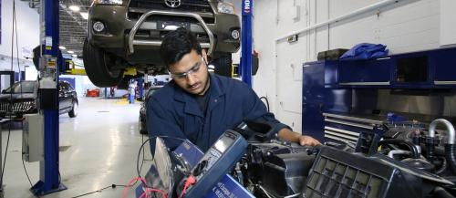 One male Motive Power Technician - Advanced Repair student runs diagnostics on a car engine.