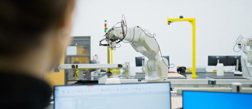 Engineering student controlling a robot arm in the robotics lab
