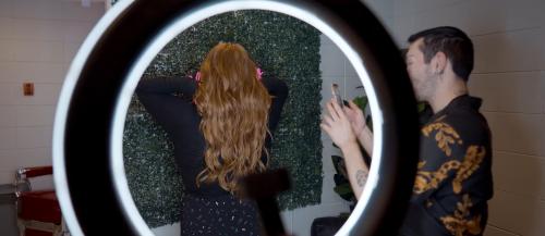 Hairstyling student taking photo of client's hair after styling