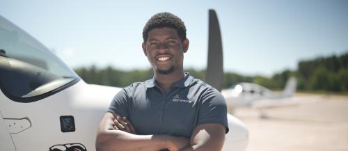 Aviation student posed smiling at camera with Ciruss aircraft in background on apron