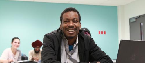 Academic Upgrading student smiling at camera in classroom
