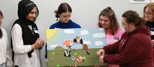 ECE students looking at felt animal scene board and moving things on it